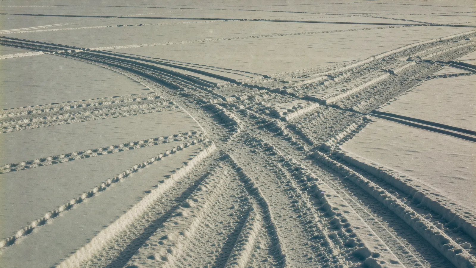 Many different paths of tracks crossing a wide snowy field